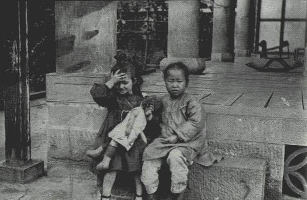 WHERE EAST MEETS WEST

Playfellows in Far Interior China. The little white girl is the daughter
of a missionary in Suifu, Szech'uan, where picture was taken on porch of
mission residence.