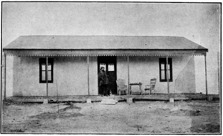 LA PREMIÈRE MAISON DE LA «COLONIA CERVANTES», EN BOIS,
DÉMONTABLE, REVÊTUE DE TÔLES DE ZINC ONDULÉ

Blasco a été photographié sur le seuil de cette baraque